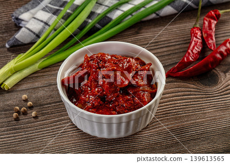 Spicy red chili pickle in a white bowl on a rustic wooden table with fresh ingredients Spicy red chili pickle in a white bowl on a rustic wooden table with fresh ingredients 139613565