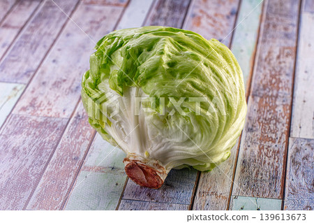 Fresh head of iceberg lettuce on a rustic multicolored wooden table background. Fresh head of iceberg lettuce on a rustic multicolored wooden table background. 139613673