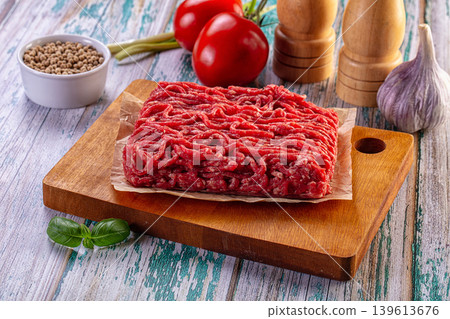 Fresh raw minced beef on a wooden board with cooking ingredients Fresh raw minced beef on a wooden board with cooking ingredients 139613676