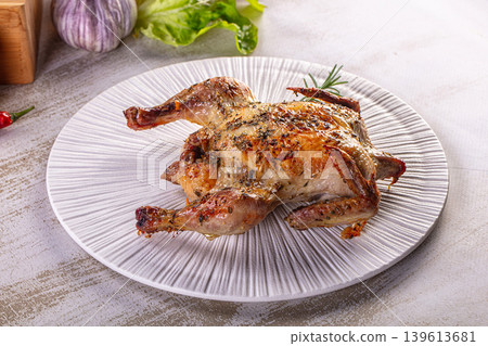 Roasted whole quail with herbs and spices on a white plate in a rustic setting. Roasted whole quail with herbs and spices on a white plate in a rustic setting. 139613681