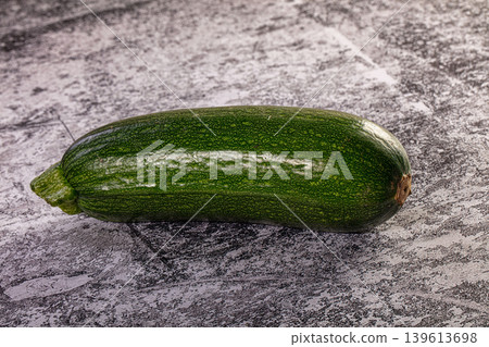 Single fresh green zucchini on a textured stone background Single fresh green zucchini on a textured stone background 139613698
