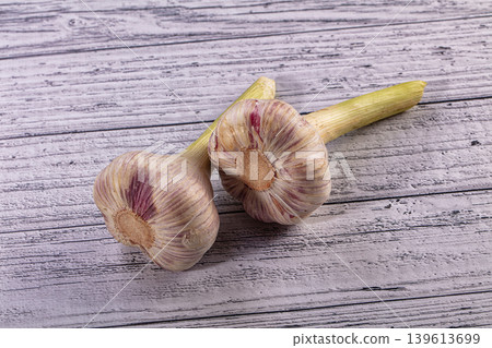 Two fresh garlic bulbs with purple streaks on a rustic wooden table Two fresh garlic bulbs with purple streaks on a rustic wooden table 139613699
