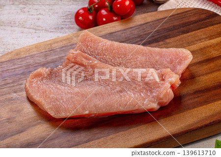 Raw turkey breast fillets on wooden cutting board with fresh cherry tomatoes, garlic, chili pepper, and basil Raw turkey breast fillets on wooden cutting board with fresh cherry tomatoes, garlic, chili pepper, and basil 139613710