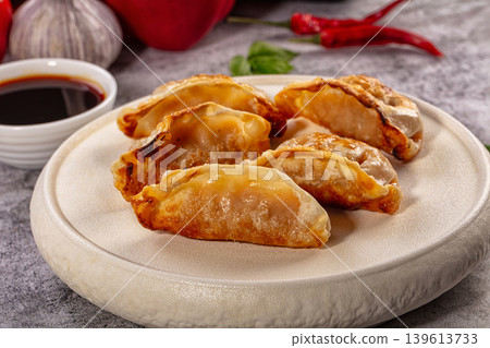 Fried gyoza dumplings on ceramic plate with soy sauce and fresh ingredients Fried gyoza dumplings on ceramic plate with soy sauce and fresh ingredients 139613733