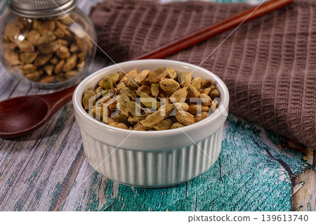 Aromatic green cardamom pods in white bowl on rustic wooden background 139613740