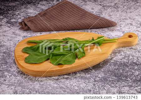 Fresh green arugula leaves on wooden cutting board over rustic background 139613743