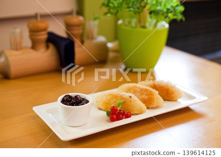 Fried sweet dumplings with cherry jam and redcurrant garnish on wooden table Fried sweet dumplings with cherry jam and redcurrant garnish on wooden table 139614125
