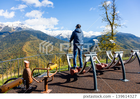 Man exercises outdoors while facing mountains with snow on top Man exercises outdoors while facing mountains with snow on top 139614327