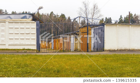 Fenced area with trees. Walled compound featuring functional facilities and natural greenery surroundings Fenced area with trees. Walled compound featuring functional facilities and natural greenery surroundings 139615335