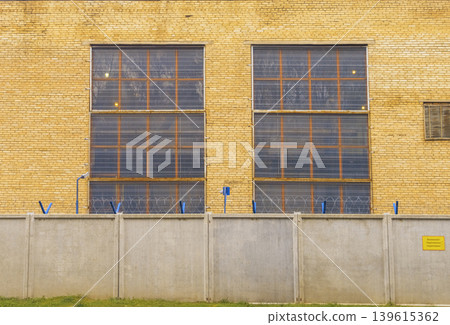 Aged industrial look with light shadows. Repetitive grid with warm yellow bricks and window pattern 139615362
