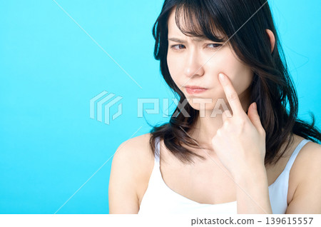 一位神情憂慮的日本年輕女子指著自己的臉頰;畫面顯示她有皮膚問題。 一位神情憂慮的日本年輕女子指著自己的臉頰;畫面顯示她有皮膚問題。 139615557