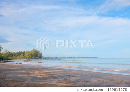 Beautiful serene tropical beach landscape with calm blue sea, white sand, and pine trees along the coast under a clear blue sky with soft clouds. Perfect peaceful summer vacation getaway background. Beautiful serene tropical beach landscape with calm blue sea, white sand, and pine trees along the coast under a clear blue sky with soft clouds. Perfect peaceful summer vacation getaway background. 139615978