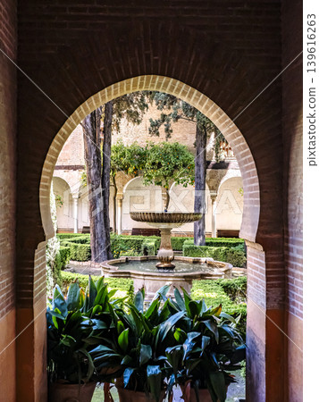 Historic Courtyard Fountain Through Moorish Archway in Lush Alhambra Garden With Orange Trees Historic Courtyard Fountain Through Moorish Archway in Lush Alhambra Garden With Orange Trees 139616263
