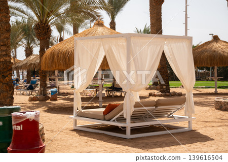 White beach cabana with lounge chairs on sandy resort coast in Sharm El Sheikh Egypt near the Red Sea. Beach travel and resort lifestyle White beach cabana with lounge chairs on sandy resort coast in Sharm El Sheikh Egypt near the Red Sea. Beach travel and resort lifestyle 139616504