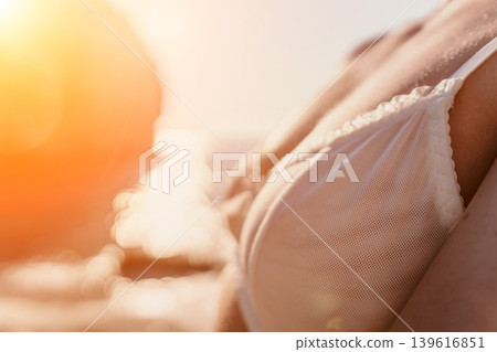 Woman lingerie beach close up of white lace bra on sun-drenched skin during golden hour with copy space Woman lingerie beach close up of white lace bra on sun-drenched skin during golden hour with copy space 139616851