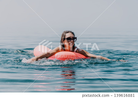 Woman floating relaxing on inflatable mattress in blue ocean water on sunny summer day Woman floating relaxing on inflatable mattress in blue ocean water on sunny summer day 139616881