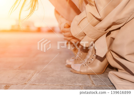 Trench coat shoes sunset woman crouching in stylish heels on pavement during golden hour with copy space for lifestyle 139616899