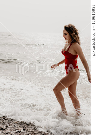 Woman Beach Swimsuit walking through the ocean surf during a happy summer vacation on a sunny coastline 139616955