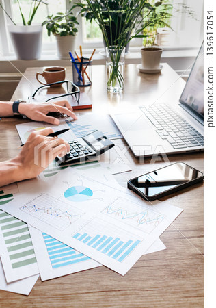 Businessperson working with financial data and charts on wooden desk Businessperson working with financial data and charts on wooden desk 139617054