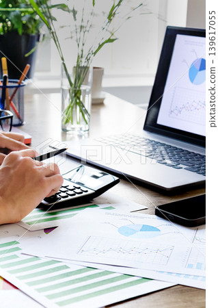 Close-up: Hand calculating financial figures on wooden desk Close-up: Hand calculating financial figures on wooden desk 139617055
