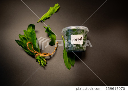 Fresh green sorrel leaves in plastic container on dark background 139617070