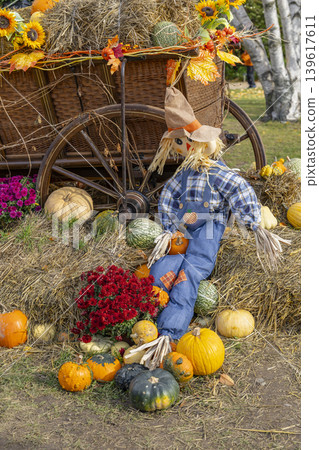 Scarecrow sitting on hay bales with autumn harvest decoration Scarecrow sitting on hay bales with autumn harvest decoration 139617611