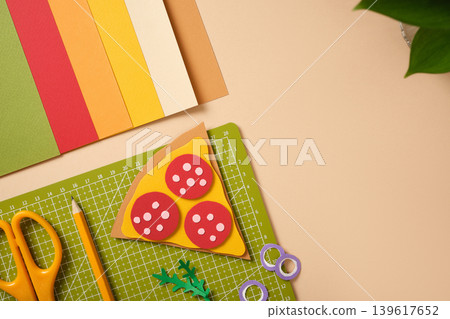 Top view of a DIY paper pizza craft on a green cutting mat with copy space. 139617652