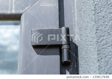 A close view of a window hinge shows its design and attachment to the frame in a well-lit space with natural light 139617696