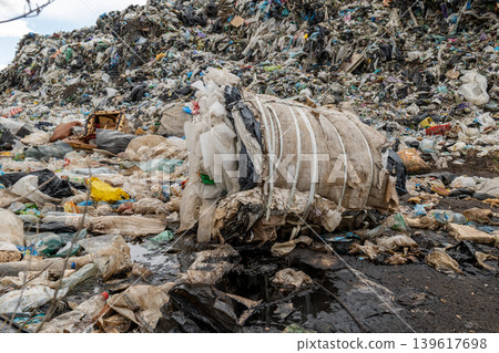Large garbage landfill contains various types of waste, plastic, and debris in an urban setting during the day Large garbage landfill contains various types of waste, plastic, and debris in an urban setting during the day 139617698