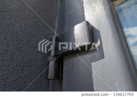 New door hinges are attached to a black door in a residential area under clear skies during the afternoon New door hinges are attached to a black door in a residential area under clear skies during the afternoon 139617705