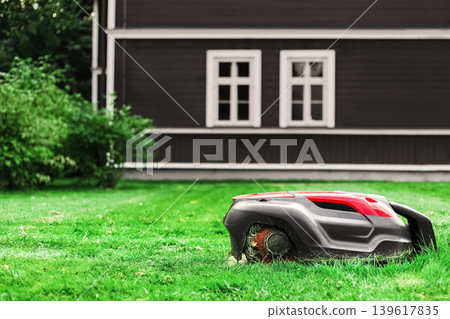 A modern robotic lawn mower automatically cuts grass.Ideal for smart home, eco-friendly gardening, and artificial intelligence themes. A modern robotic lawn mower automatically cuts grass.Ideal for smart home, eco-friendly gardening, and artificial intelligence themes. 139617835