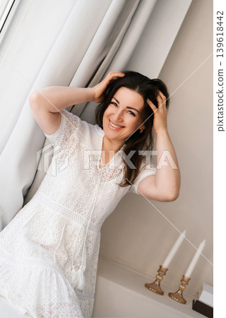 Smiling Brunette Woman Sitting by Window Light 139618442
