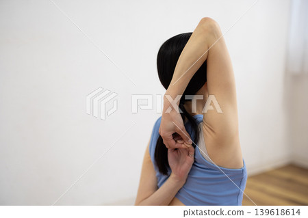 一位中年日本婦女在墊子上擺出牛臉的姿勢。 139618614