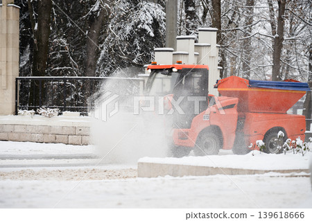 Compact municipal snow sweeper with rotary brush . Snow removal concept . A sweeper moves along a snow-covered street Compact municipal snow sweeper with rotary brush . Snow removal concept . A sweeper moves along a snow-covered street 139618666