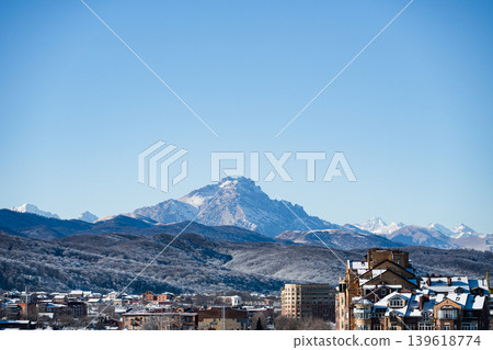 Sprawling town nestled against a backdrop of snow-capped mountains . Sprawling town nestled against a backdrop of snow-capped mountains . 139618774