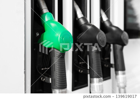 Close-up of fuel pump nozzles at a modern gas station, focus on green gasoline dispenser. Concept of energy, transportation and rising fuel prices. 139619017