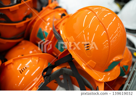 Orange construction helmets arranged together at a building site. Bright safety hard hats used for head protection in industrial and construction environments. Orange construction helmets arranged together at a building site. Bright safety hard hats used for head protection in industrial and construction environments. 139619032
