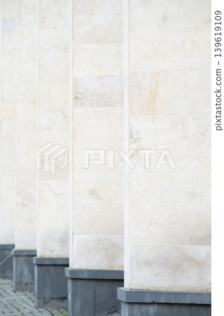 Vertical perspective of white marble columns with repetitive geometric pattern in modern architecture. Repetition of white stone columns with selective focus as abstract urban background. Vertical perspective of white marble columns with repetitive geometric pattern in modern architecture. Repetition of white stone columns with selective focus as abstract urban background. 139619109