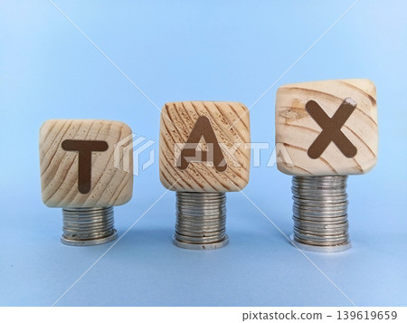 Tax concept with cube blocks or wooden blocks on top of a stack of coins. Economy and finance 139619659