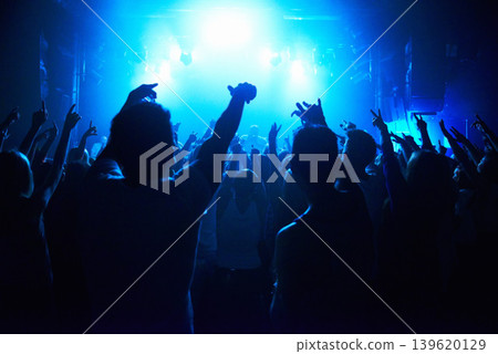 Nightclub, people and crowd with energy and lights for party, concert or rave festival with spotlight and dancing. Disco, psychedelic event and performance with entertainment, audience and rear view Nightclub, people and crowd with energy and lights for party, concert or rave festival with spotlight and dancing. Disco, psychedelic event and performance with entertainment, audience and rear view 139620129