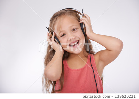 Child, music and portrait of girl with headphones in studio for audio, subscription and streaming multimedia on white background. Excited kid listening to podcast, hearing sound and radio connection Child, music and portrait of girl with headphones in studio for audio, subscription and streaming multimedia on white background. Excited kid listening to podcast, hearing sound and radio connection 139620221