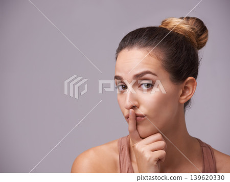Portrait of woman, finger on lips or silence for secret, mystery or privacy in gossip on grey background. Mouth, natural face or confident model isolated in studio with beauty for skincare or hush Portrait of woman, finger on lips or silence for secret, mystery or privacy in gossip on grey background. Mouth, natural face or confident model isolated in studio with beauty for skincare or hush 139620330