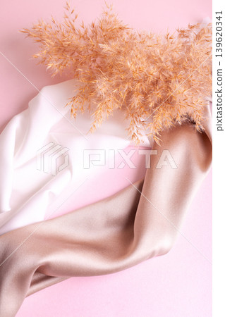 Abstract background in soft colors of silk fabrics on pink pearl paper and branch Dry beige reed. Beautiful trend texture Abstract background in soft colors of silk fabrics on pink pearl paper and branch Dry beige reed. Beautiful trend texture 139620341