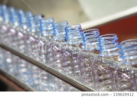 Close-up incline view of a clear plastic PET drinking water bottle with light reflection and blue tone. Close-up incline view of a clear plastic PET drinking water bottle with light reflection and blue tone. 139620412