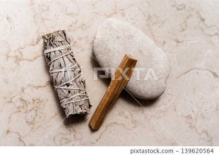 White sage bundle, palo santo stick on smooth stone on a light marble background White sage bundle, palo santo stick on smooth stone on a light marble background 139620564