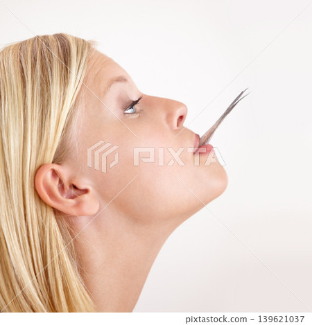 Woman, eating and tail of fish in mouth or hungry for strange food in white background, studio or mockup. Crazy, diet and person bite weird seafood, cuisine and try a taste of tuna or salmon meat 139621037