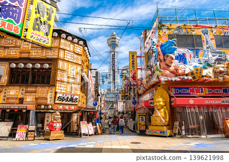 Osaka City: The lively scene of Shinsekai, with Tsutenkaku Tower standing out against the blue sky and giant 3D billboards lining the streets. Osaka City: The lively scene of Shinsekai, with Tsutenkaku Tower standing out against the blue sky and giant 3D billboards lining the streets. 139621998