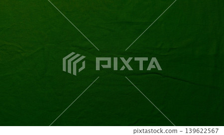rich emerald green textured fabric closeup with deep wrinkles and dramatic dark crack 139622567
