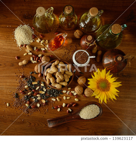Top view of gourmet oil assortment with sunflower peanuts flax seeds and sesame on rustic wooden tabletop Top view of gourmet oil assortment with sunflower peanuts flax seeds and sesame on rustic wooden tabletop 139623117
