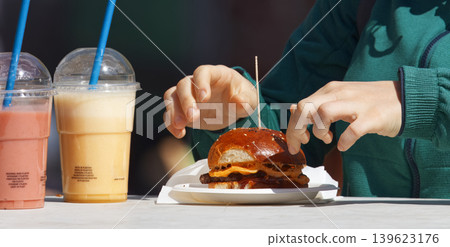 Hands reaching for burger and smoothies at food festival Hands reaching for burger and smoothies at food festival 139623176